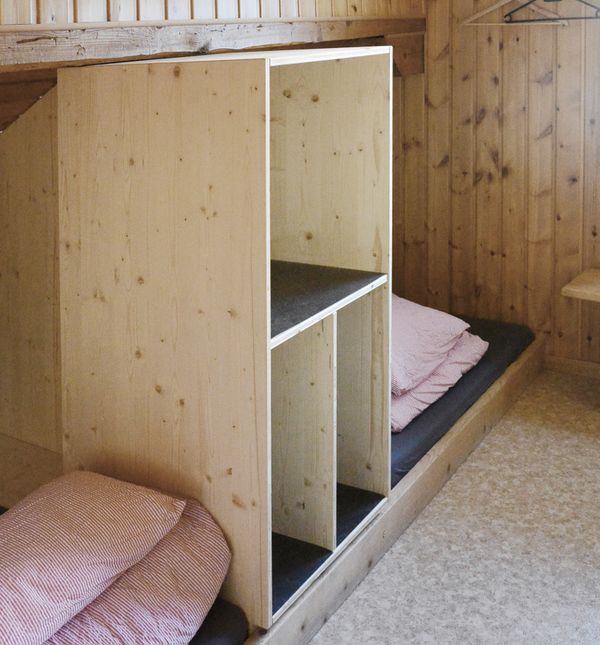 Schlafstätten mit Bettwäsche, abgetrennt durch ein praktisches Holzregal 