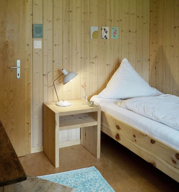 Berggasthaus Gitschenen Zimmer mit Holzbett und weisser Bettwäsche