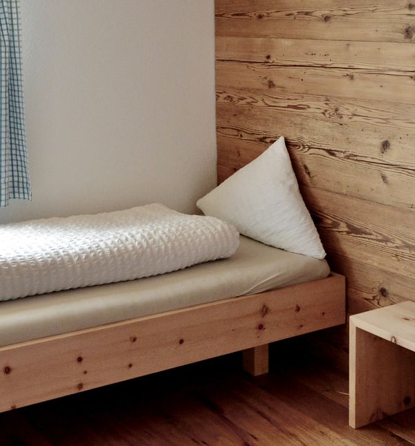 Holzbett mit weisser Bettwäsche